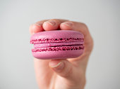 Purple sweet macaroon cookies in hand on a white background. Close-up, air-conditioning product