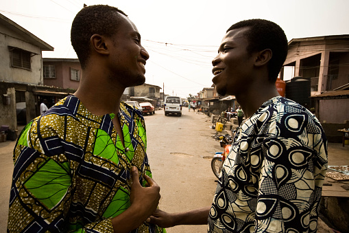 Lagos, Nigeria - January 22, 2010: Two young men having a friendly talk on the street in the ghetto of Lagos, one of the fastest growing cities in Africa.