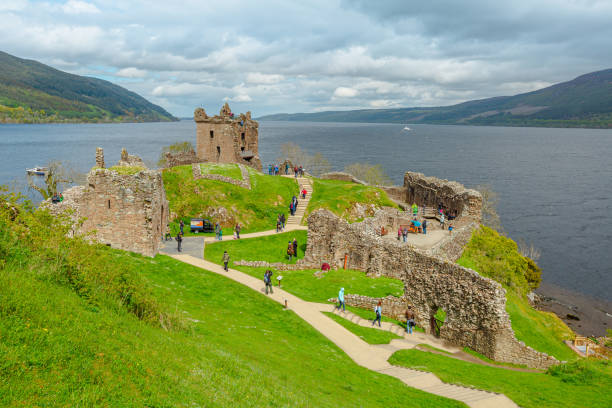 Urquhart Loch Ness Castle tourists Loch Ness, Scotland, United Kingdom - May 24, 2015: aerial view of tourists visiting Urquhart Castle beside Loch Ness lake. Visited for the legend of the Loch Ness monster: Nessie. drumnadrochit stock pictures, royalty-free photos & images