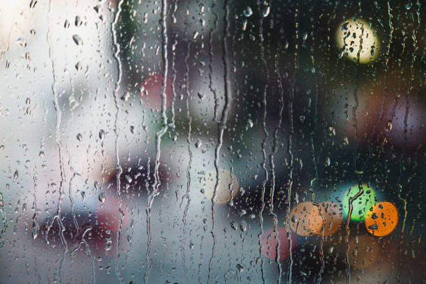 istock Abstract raindrops on window with colorful bokeh from city traffic background 1341229115
