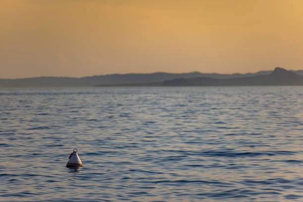 Italy - Lake Garda in the town of Torri del Benaco. Sunset, a buoy floating on the water, in the distance you can see the tops of the mountains.