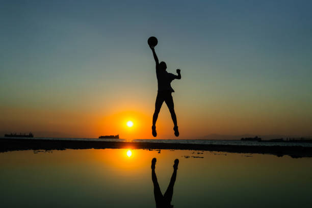 Young man practices basketball at sunset