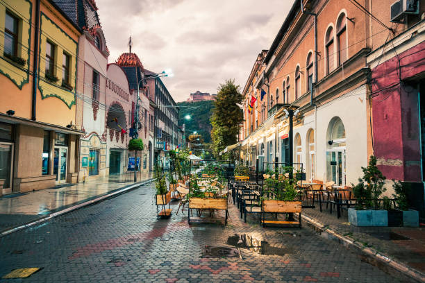A city street after a rain storm in Deva, a small city in Transylvania, Romania. The street is lined with bars and restaurants, and in the distance is the ancient citadel that crowns the city.