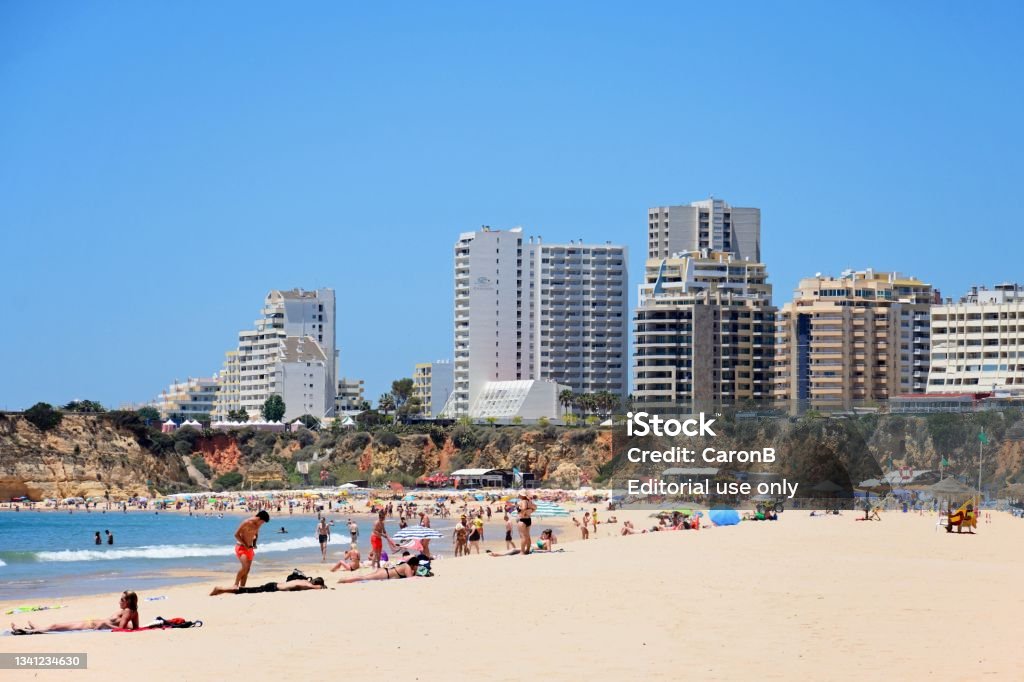 Portimao beach, Algarve, Portugal. View along the beach with apartments and hotels to the rear and tourists enjoying the setting, Portimao, Algarve, Portugal, Europe. Algarve Stock Photo