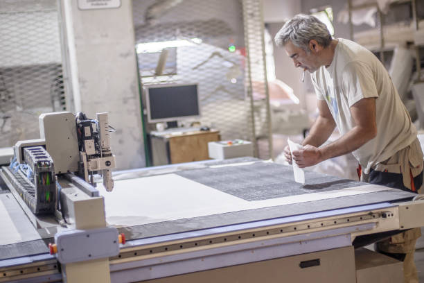 istock Technician works on CNC digital cutter machine for cutting textile 1341235432