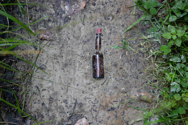 istock small brown glass bottle with a lid that is half sunk in the dirt 1341241215