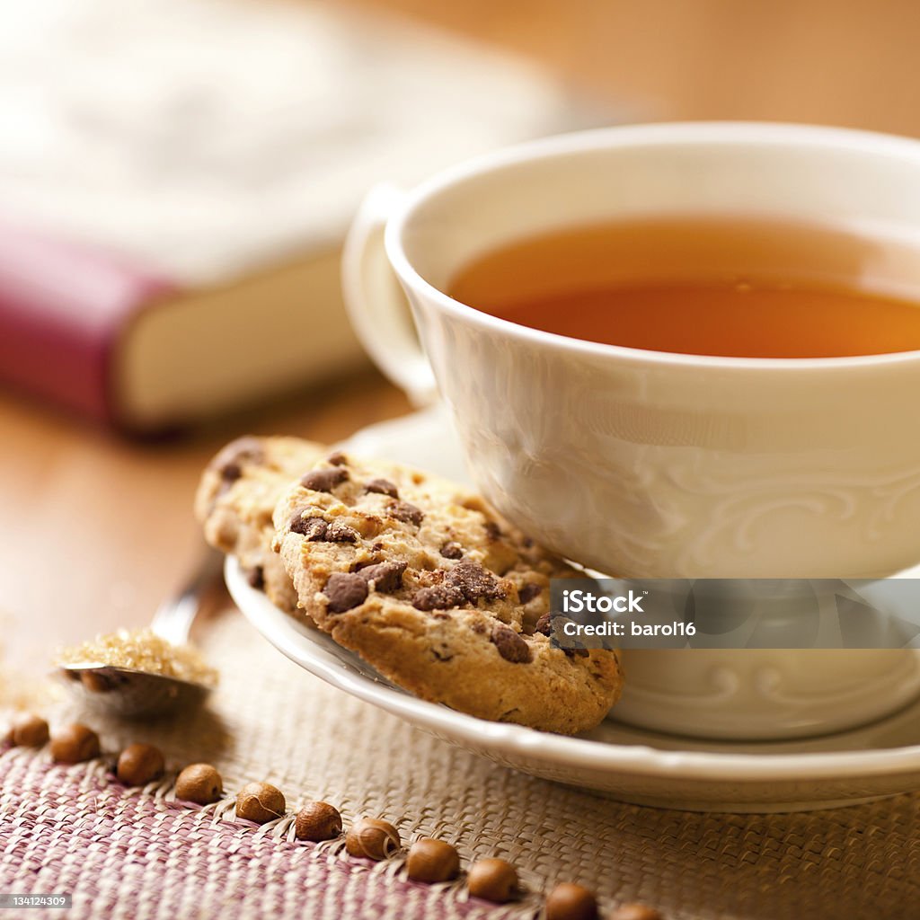 Cup of tea and chocolate chip cookies cup of tea and chocolate chip cookies; book in background Tea - Hot Drink Stock Photo