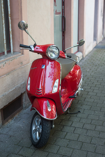 Colmar - France - 18 September 2021 - Front view of red vespa scooter parked in the street