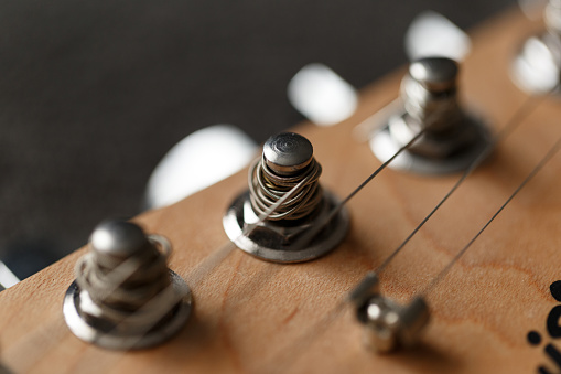 Electrical guitar headstock, machine heads and metal strings closeup. Electric guitar black and white color, detail. Music instruments. Concept international music day. Macrophotography. Soft focus