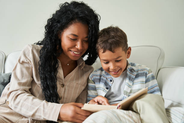istock Black mother reading book with her son on couch 1341245652