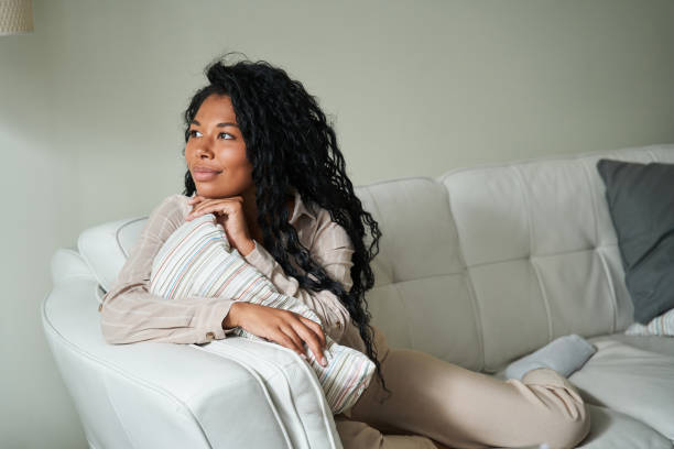 istock Young black woman sitting on couch and thinking 1341245677