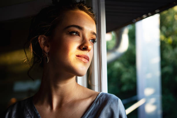 istock Beautiful young woman looking the window 1341247835