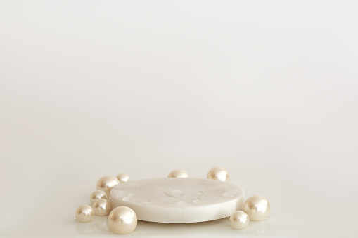White marble podium with pearls and water drops on the white background. Podium for product, cosmetic presentation. Creative mock up. Pedestal or platform for beauty products