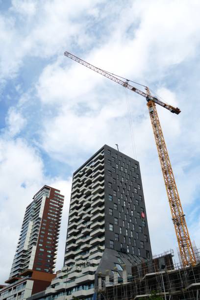 Corporate buildings building site with a crane in Rotterdam. Vertical view in low angle view. Blue sky with some white clouds on background.