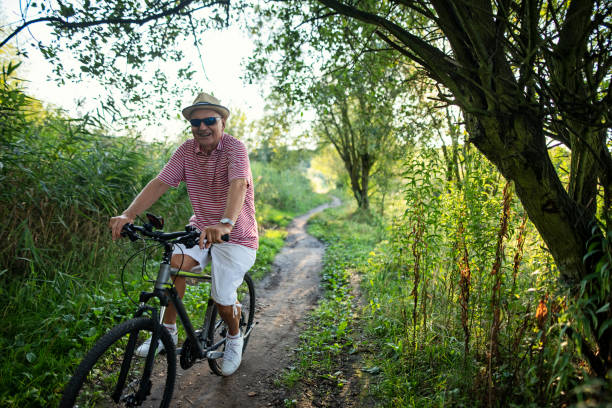 Happy senior man enjoying riding a bike on a summer day eveningNikon D850