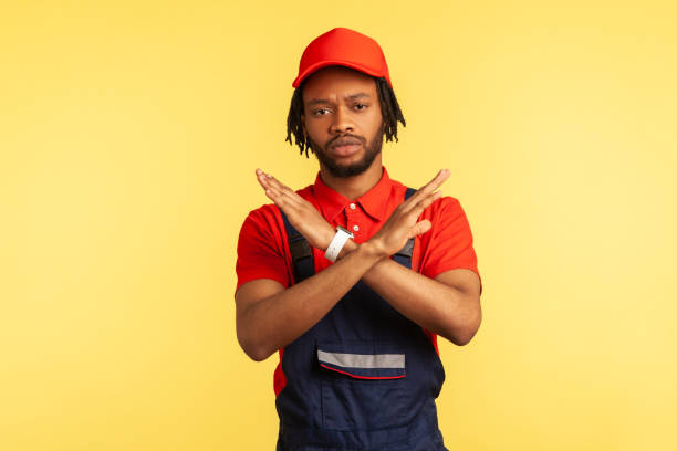 istock Workman wearing uniform, gesturing stop with crossed hands, service industry, courier delivery. 1341255045