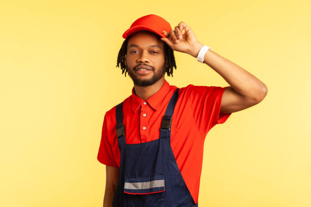 istock Handyman standing with raised arm, keeps hand on his visor cap, waiting orders in service industry. 1341255060