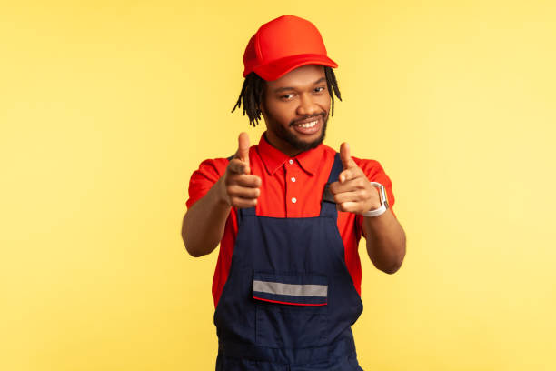 istock Positive builder or courier pointing to camera with fingers, looking with pleasant smile, service. 1341255061