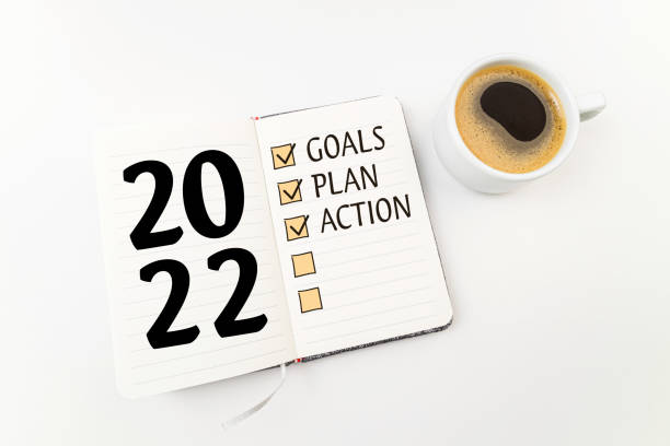 istock New year goals 2022 on desk. 2022resolutions list with notebook, coffee cup on white desk. Resolutions, plan, goals, action, checklist,  idea concept. New Year 2022 template 1341256793