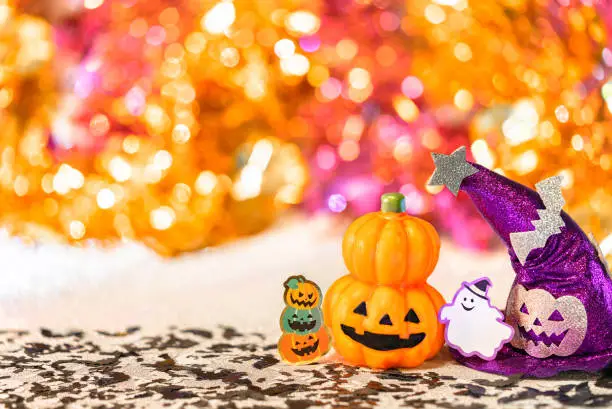 Photo of Halloween jack o lantern pumpkin and witches hat with smiling ghost  on  a shiny colorful background.