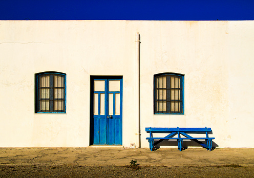 Typical Andalusian whitewashed facade with blue painted window and bench