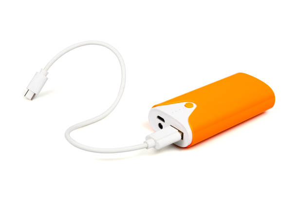 白い背景にusbケーブルが付いているオレンジ色のパワーバンク。 - mobile phone charging power plug adapter ストックフォトと画像
