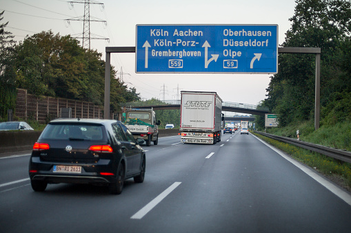 Köln, Germany - September 06, 2021: Traffic on german Autobahn A 59 nearby Kreuz Köln-Porz. Bundesautobahn 59 (abbreviated as BAB 59 or A 59) is an autobahn in Germany that starts in Dinslaken and connects the cities of Duisburg, Düsseldorf, Cologne and Bonn. Some road users in the background. Photography has been taken during driving, some motion blur