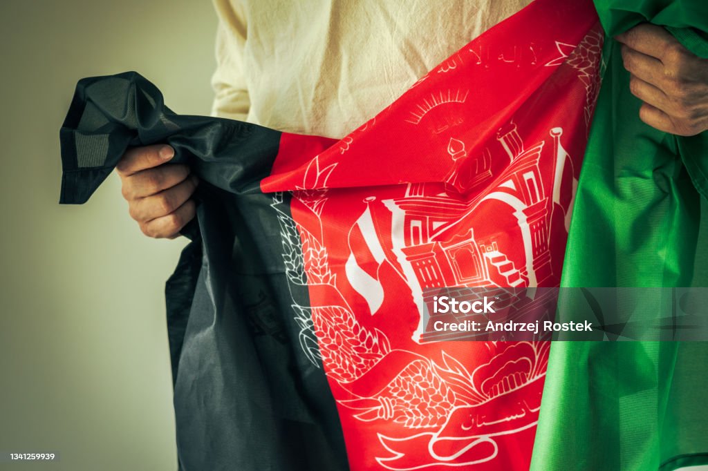 A man in traditional clothes, holding the flag of Afghanistan in his hands Afghanistan Stock Photo