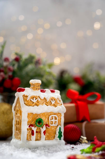 istock Gingerbread house with Christmas decorations, red baubles, fir branches, gift boxes and bokeh lights. 1341260011