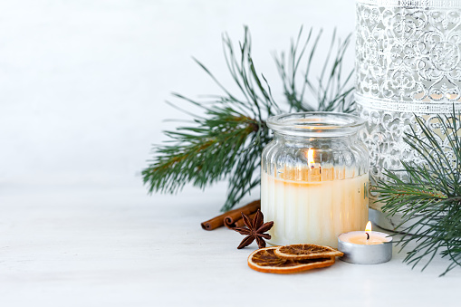 Rustic zero waste natural christmas decor. Candle in glass jar, spices, dry orange, green fir tree banches. Decoration for holiday dinner table. Happy new year. Holiday atmospere, festive mood