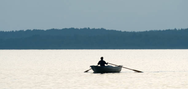 istock Rear view on lonely man in boat rowing on lake 1341267048
