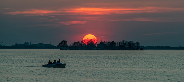 Silhouettes of people in boat on lake at sunset