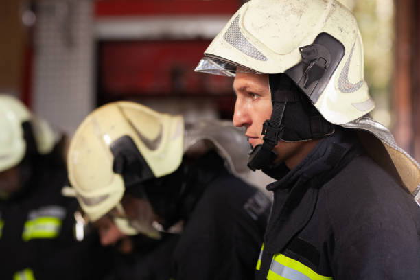 istock Professional firefighters wearing uniforms and protective helmets. Firetruck in the background. 1341267440