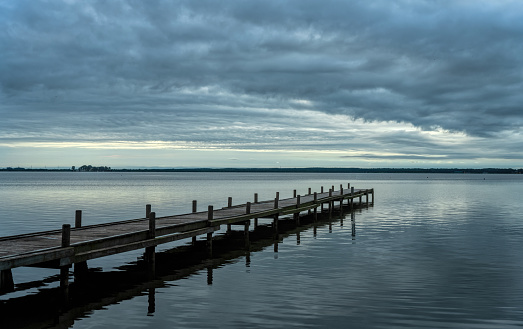 Silhouette of jetty with dark cloudscape after rain at lake Steinhuder Meer, Lower Saxony, Germany