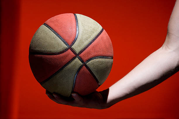 istock Basketball ball in hand isolated on red background 134127155