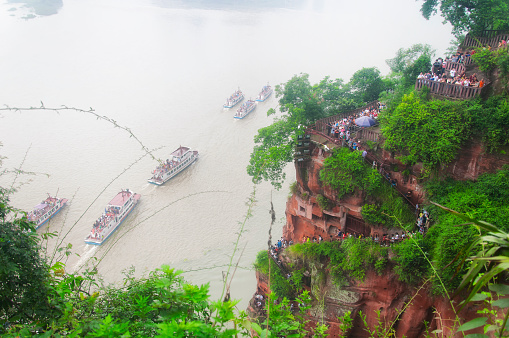 June 24, 2018.  Leshan, China. looking down at the tourist boats and tourist walking down the steps within the leshan grand buddha scenic area in Sichuan province china.