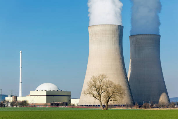 istock Nuclear power station with two white steaming cooling towers and clear blue sky. 1341271647