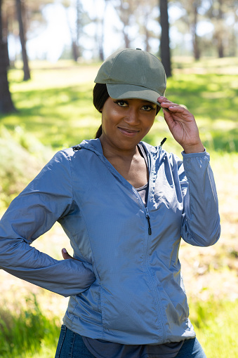 Young African woman with cap outdoors hiking jogging in forest smiling having fun