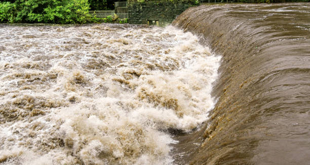 istock Heavy flood water passing over a weir on a river 1341274011