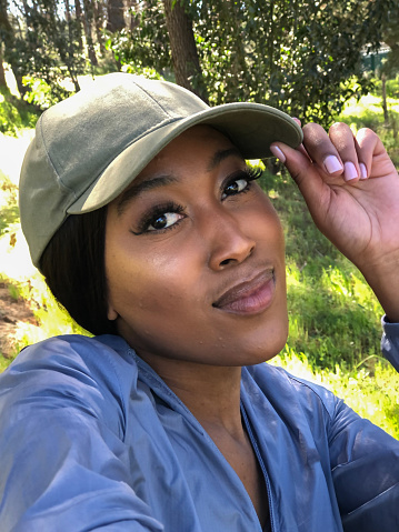 Beautiful Young African woman with long straight hair outdoor hiking selfie with cap