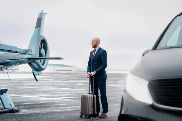 Photo of Businessman with his bag standing on airstrip by a chopper