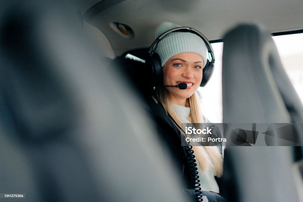 Woman sitting in helicopter wearing headset Portrait of young woman sitting in helicopter wearing headset. Female passenger sitting in a chopper looking at camera and smiling. Luxury travel concept. Aspirations Stock Photo