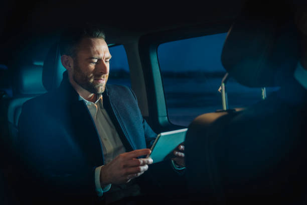 istock Businessman working on tablet computer while traveling to work in car 1341275553