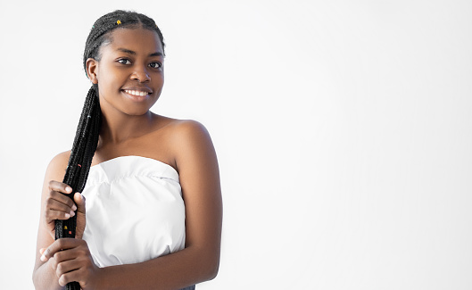 Hair care. Braids hairstyle. Professional hairdo. Beauty salon. Attractive smiling African young woman with long stylish zizi braided locks isolated on white copy space.