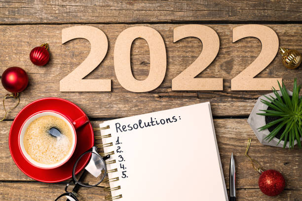 istock New year 2022 resolutions on desk. 2022 goals with notebook, coffee cup, eyeglasses, Christmas decorations on wooden table. Goals, plan, strategy, action, idea concept. New Year 2022 1341280613