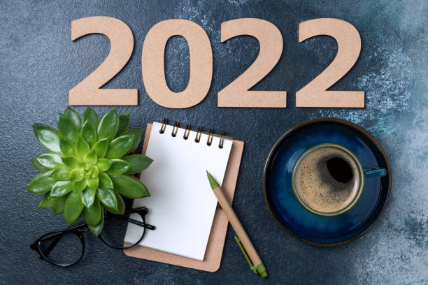 istock New year resolutions 2022 on desk. 2022 goals with open notebook, coffee cup, eyeglasses, plant succulent on blue table. Goals, plan, strategy, action, idea concept. New Year 2022 1341280619