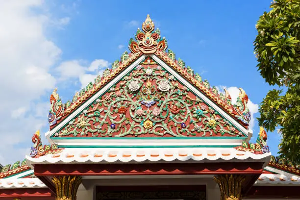 Photo of Beautiful pediment of a Buddhist temple decorated with ceramic mosaics depicting flowers