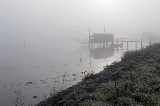 Comacchio, Italy - December 29, 2019: view of fishing house in foggy day