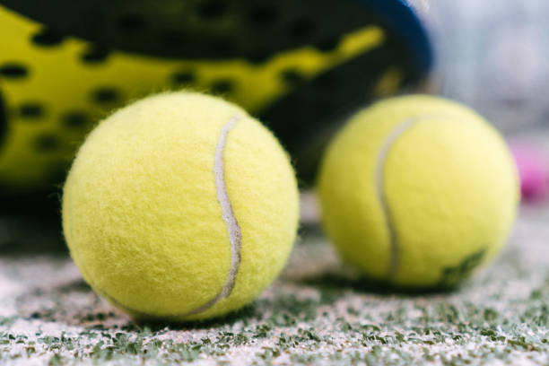 tennis ball on the artificial grass court after a paddle tennis match. tennis ball on the green artificial grass court after a paddle tennis match. ball next to the net of a paddle tennis court paddle ball stock pictures, royalty-free photos & images