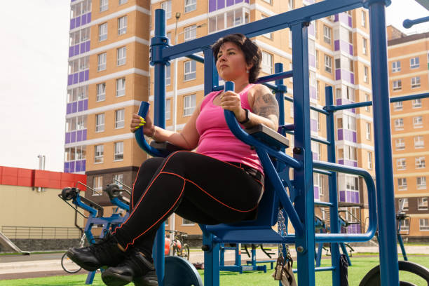 young woman performs exercises outdoors using street fitness combo machine